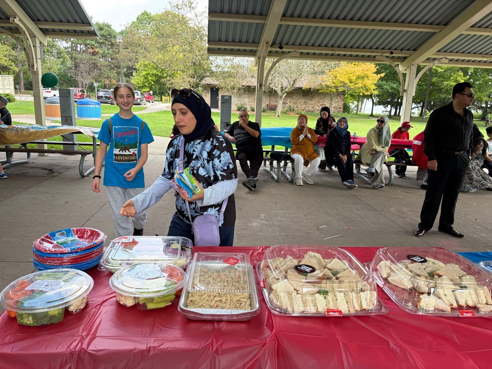 Families gather at the food table under the pavilion