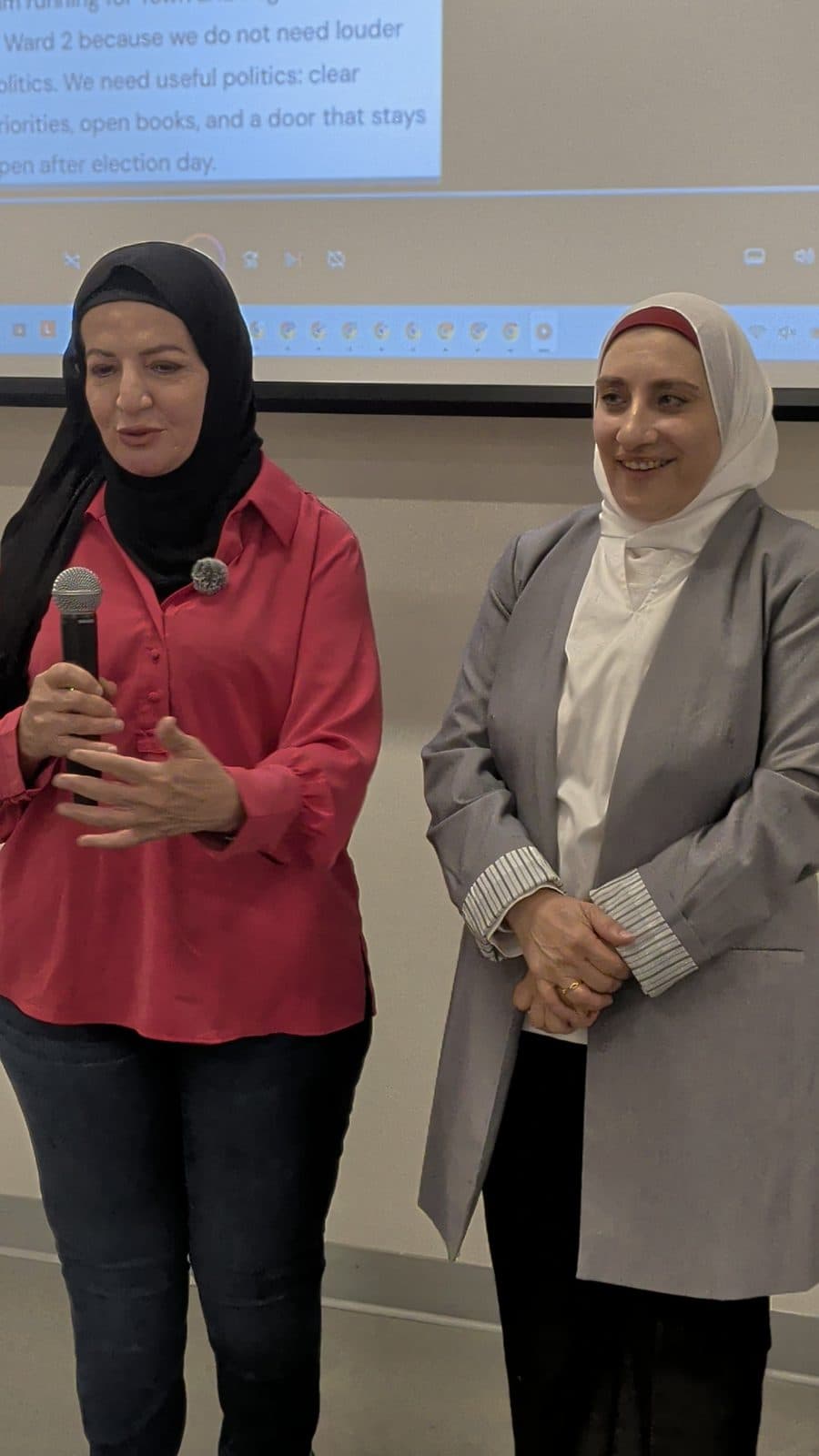 A guest in a red blouse speaks at the microphone beside Zena
